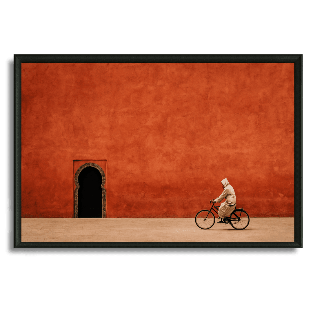 Tableau marocain cycliste en djellaba devant mur rouge et arche traditionnelle